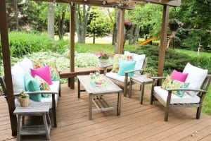 colorful outdoor space makeover using thrifted furniture, globe lights, and vivid pillows