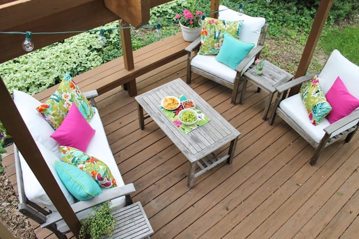 colorful outdoor space makeover using thrifted furniture, globe lights, and vivid pillows